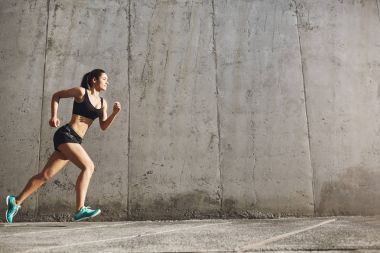 Güçlü kadın fitness hayatında başarı için ileri çalıştırıyor. Kentsel spor kavramı.