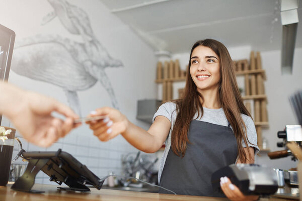 Female barista interacting with customer using a bank terminal to process and acquire credit card payments.