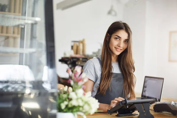 Coffee shop owner using a tablet looking at camera smiling, ready for her first customer Stock Picture