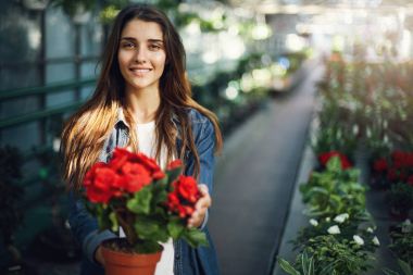 Güzel kadın bahçıvan kamera gülümseyen seyir çiçek Bakımı.