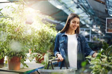 Güzel kız bir mağazada yeşil bitkiler için alışveriş. Annesi bir hediye ile sürpriz yapmak planlama.