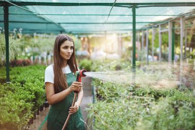 Havalı kadın bahçıvan sulama o seviyor bitkiler ve önemser. Genç girişimci onun iş grow için mücadele.