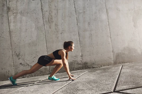 Genç atlet ileri onun günlük kentsel iş günü dürtmek hazırlanıyor. Tan kız çevreleyen beton duvarlar.