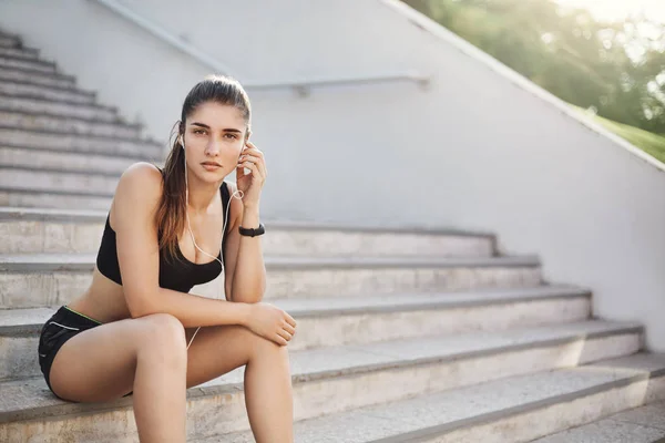 Junge und selbstbewusste Fitnesstrainerin, die fröhliche Musik hört, um ihr tägliches urbanes Workout auf einer Treppe zum perfekten Körper zu beginnen. — Stockfoto