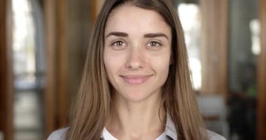 Closeup posh Üniversitesi Öğrenci portresi. Güzel genç kadın gülümseyerek ve çalışma iç gülüyor kamera bakıyor. Ağır çekim.