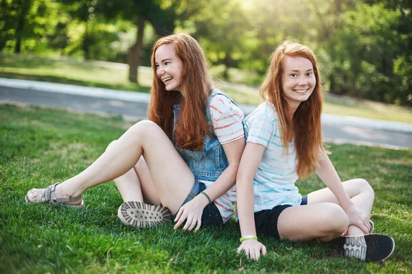 Pár egypetéjű ikrek gyömbér nővérek szórakozás szabadtéri parkban. Véletlen vagy kemény munka, a szülők. Barátság koncepció. — Stock Fotó
