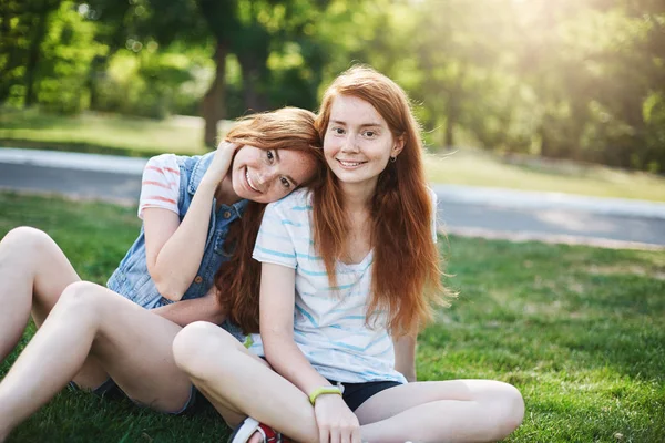 Ginger tvillingflickor att ha en bra dag utanför i parken på en solig sommardag. Ungdom vänskap och slarvig tid tillsammans. — Stockfoto