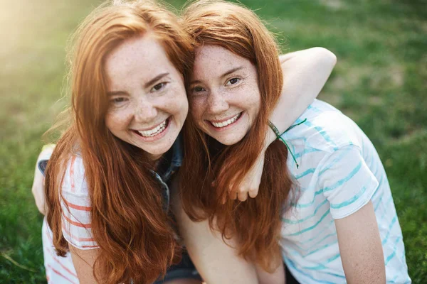 Två identiska systrar har så mycket gemensamt. Kramar, leende, spendera tid tillsammans utomhus en solig dag. Tvillingar är vad pojkar drömmer om. — Stockfoto