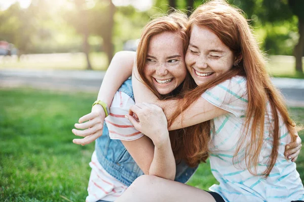 Menina abraçando sua irmã mais velha sorrindo. Duas senhoras ruivas a divertirem-se imenso. . — Fotografia de Stock