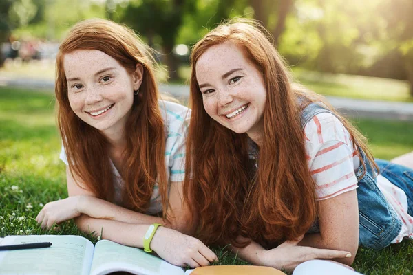Gyömbér iker lányok kiadások a nyári iskolai szünet, hogy készen áll, hogy egyetemi vizsgák. Jövőben orvos és szórakoztató ügyvéd mosolyog egy napfényes nap a parkban. — Stock Fotó