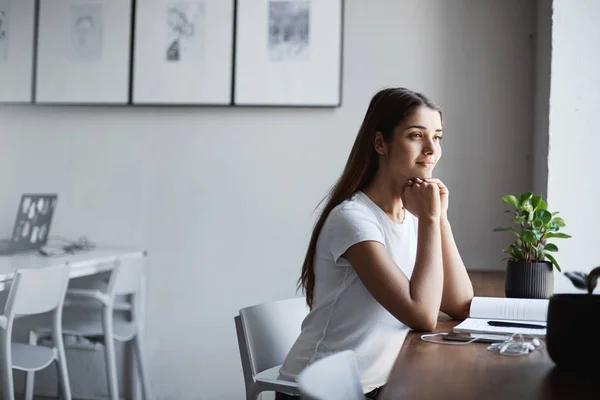 밝은 coworking에 앉아 그녀의 경력 경로에 결정 하는 젊은 아가씨 공부 하는 공간. 웃 고 밖에 서 찾고. — 스톡 사진