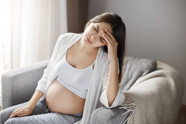 Jovem grávida que sofre de dor de cabeça e dor de cabeça. Ignorando seus medicamentos para manter um bebê saudável . — Fotografia de Stock