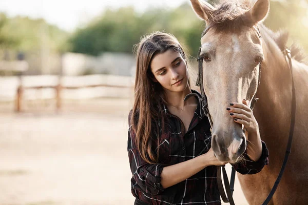 Jovem gerente de fazenda assistente feminino se preocupando com um cavalo . — Fotografia de Stock