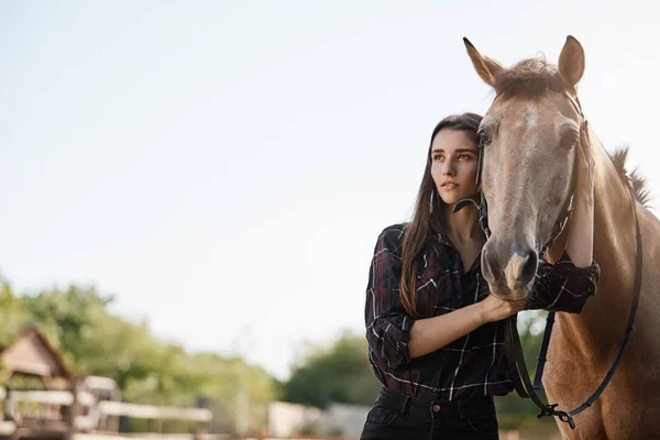 Amplo tiro de uma jovem bela gerente de fazenda assistente feminina andando um cavalo para estábulos . — Fotografia de Stock