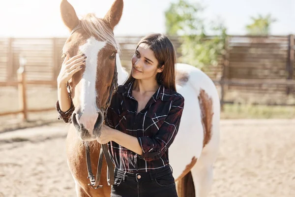 Jovem fêmea broodmare cuidando e acariciando um cavalo na fazenda de animais em um dia quente de outono . — Fotografia de Stock