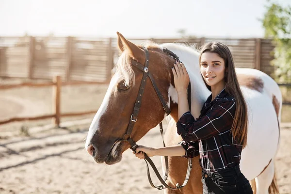 Jovem veterinário feminino acalmando um cavalo doente olhando para a câmera sorrindo . — Fotografia de Stock