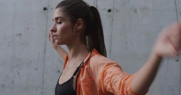 Porträt einer jungen schönen Frau, die sich vor einem Outdoor-Training aufwärmt. Stadtsportkonzept. Zeitlupe. — Stockvideo