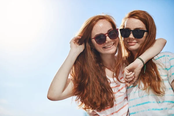 色合いを着て 2 つの赤ヘッド双子。笑みを浮かべてカメラを見ての日当たりの良い夏の日に黒眼鏡姉妹女の子。サポートの親友がある運. — ストック写真