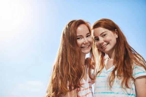 Twee meisjes kijken camera glimlachen op een zonnige zomerdag gember. Na een tweelingzus is een groot geluk. — Stockfoto