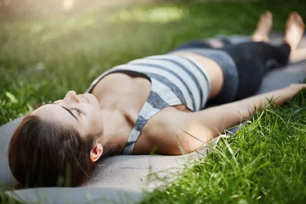 Zblízka mladé fenky, meditaci a relaxaci na jógu trávy v městském parku za slunečného letního dne. — Stock fotografie