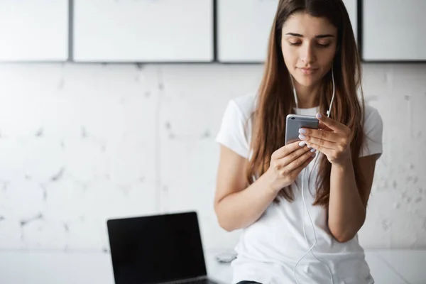 Wanita muda cantik yang baik menggunakan telepon pintar untuk menguji aplikasi barunya sebelum diterbitkan. Berkonsentrasi pada pekerjaannya . — Stok Foto