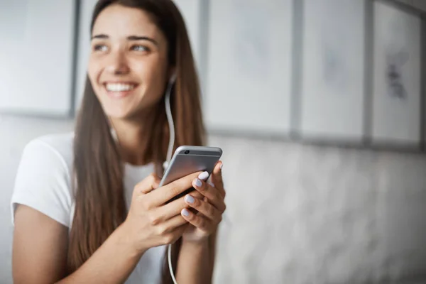 ปิดสมาร์ทโฟนในมือผู้หญิง ผู้หญิงฟังเพลงสตรีมมิ่งออนไลน์ หัวเราะและยิ้ม . — ภาพถ่ายสต็อก