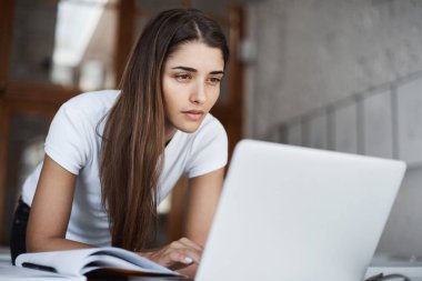 Genç güzel öğrenci Üniversite Kütüphanesi hakkında yeni bilgi için arama bir dizüstü bilgisayarda internet tarama.