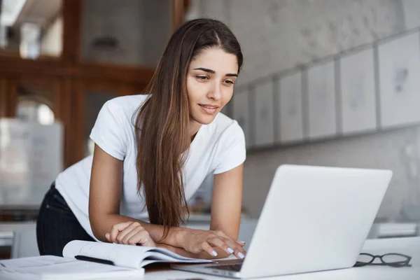 Bella donna allegra che utilizza il computer portatile nello spazio aperto coworking studio. Navigazione social network . — Foto Stock