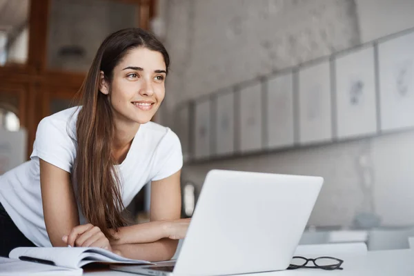 Potret seorang pengusaha perempuan muda yang percaya diri yang berdiri di dekat komputer laptop melihat ke depan ke rumah jutawan masa depannya . — Stok Foto