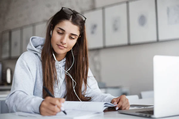Genç öğretmen meditatif müzik gözlüklü sonraki sınıf için hazırlık yazmaya konsantre.