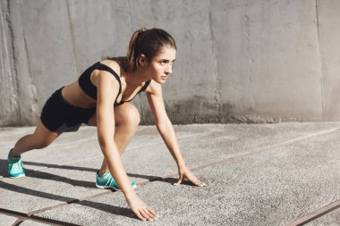Genç fit atlet kalkışa hazır portresi. Sportif vücudu hakkında dikkat çekici kadın.