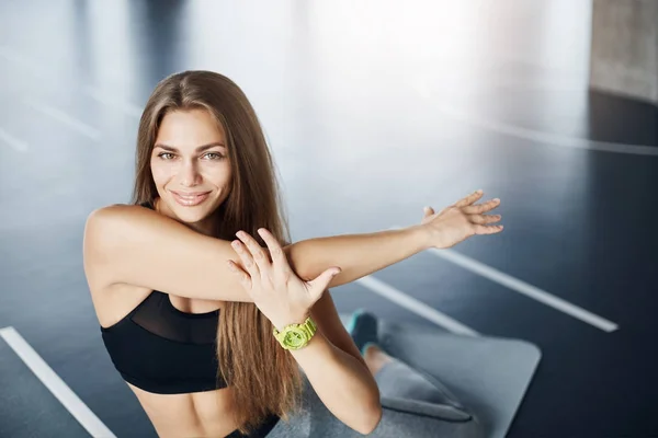 Retrato de la entrenadora de fitness corporal estirando los brazos preparándose para un duro día de entrenamiento. Mirando a la cámara sonriendo. Atleta feliz . —  Fotos de Stock