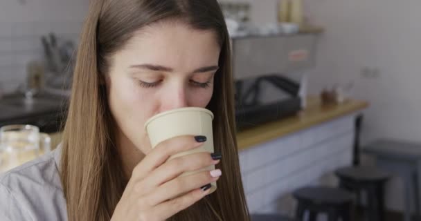 Porträtt av ung vacker kvinna dricka cappucino från ett papper Engångsskålen att få sitt morgonkaffe fixa att få hjärna kör. Glad tjej och hennes sorgliga hjärta. — Stockvideo