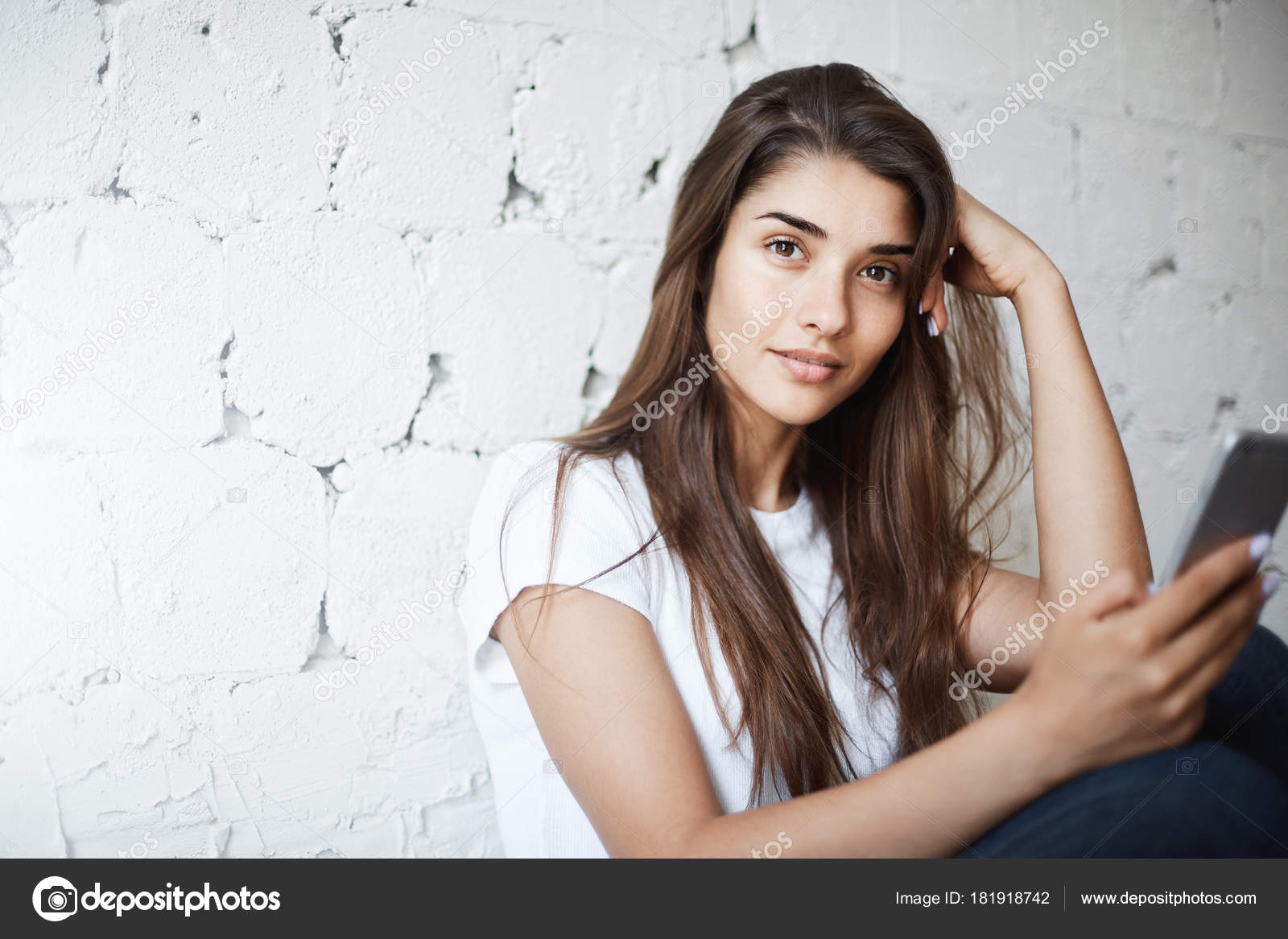 Charming European Model Sitting On Floor And Leaning On Brick Wall