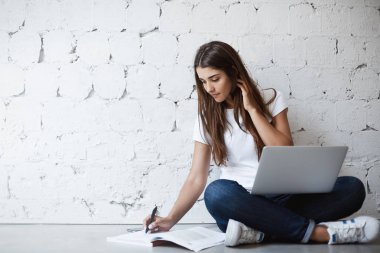 Duvara yaslanmış iken ona boyun el ile dokunmak kitapta, notlar yapma çapraz eller, laptop ile katta oturan zeki çekici kadın çevirmen, portresi. Kız proje bitirmek çalışır