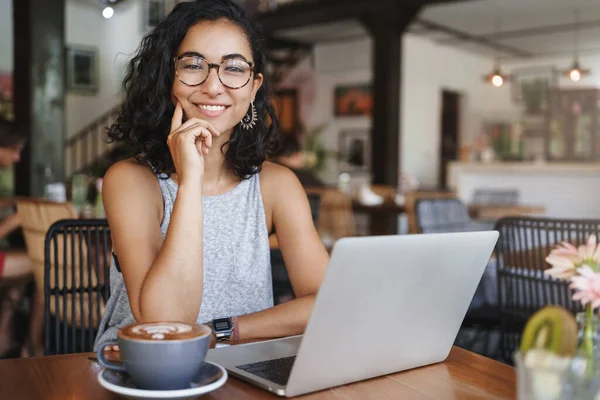 Bedrijfs-, bedrijfs- en wervingsconcept. Vrolijke goed uitziende vrouwelijke freelancer, jonge hipster meisje student zitten coworking plaats, cafe, glimlachen als met behulp van laptop en koffie drinken, hr hebben vergadering — Stockfoto