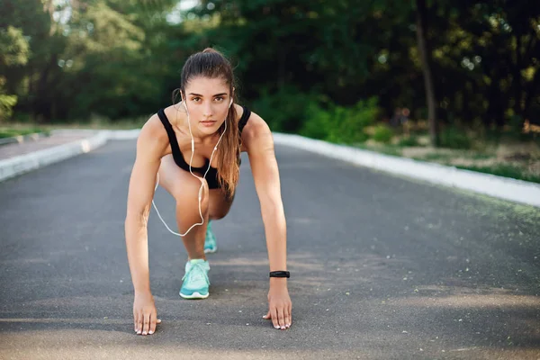 Sport, fitness and urban lifestyle concept. Motivated good-looking woman lead active life, doing morning run, sprinter stand low start on concrete road, look camera determined, jogging training — Stock Photo, Image