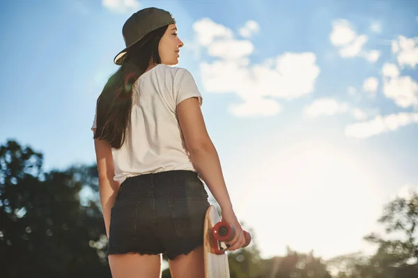 Gaya hidup perkotaan, olahraga dan konsep pemuda. Sudut bawah pemandangan wanita cantik dengan celana pendek dan kilas balik memegang papan sen kayu, berpaling bijaksana, naik skateboard selama cuaca cerah — Stok Foto