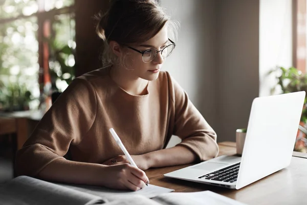 Negócios, educação, conceito freelance. Menina muito milenar em óculos trabalhando com laptop, café sit, co-working espaço universitário, preparar exames, escrever notas — Fotografia de Stock