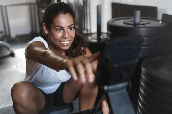 Endurance, workout and fitness concept. Happy and motivated woman with sweat on face, program equipment during training session, smiling delighted, pushing weight with legs as using leg press — 스톡 사진