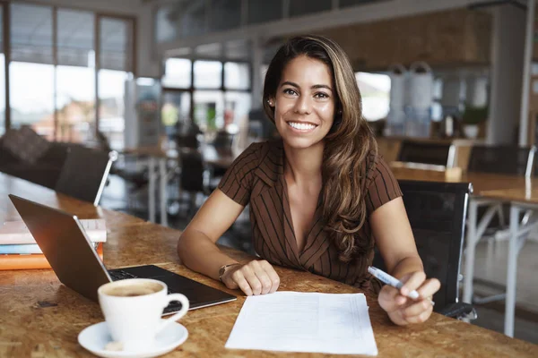 Zakelijk, financieel en ondernemersconcept. Gelukkig vrolijke aantrekkelijke Spaanse vrouw zit alleen cafe, co-working ruimte met geopende laptop, werken op afstand, koffie drinken en papier lezen, studeren — Stockfoto
