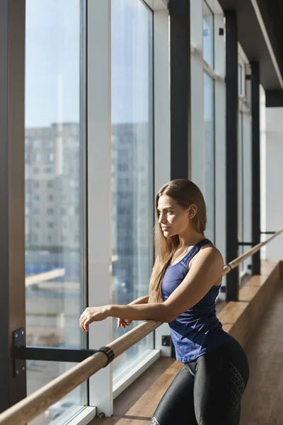 Vertical-shot elegant sexy caucasian woman, athletic sportswoman in activewear, leaning dance handrail, looking at cityscape, beautiful morning scenery from gym window, workout alone, dance in studio — Stock Photo, Image