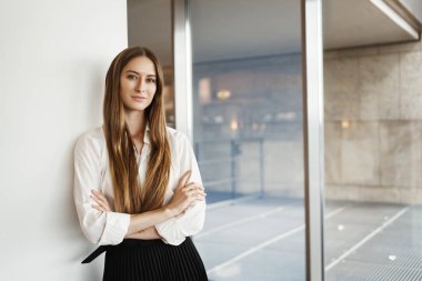 Başarılı genç iş kadını. Duvara yaslandı ve ellerini göğsüne koydu. Kendine güveni tam, özgüveni tam, hazır, şirketi için büyük bir finansal anlaşma imzaladı.