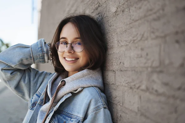 Detailní boční portrét rozkošné mladé teploušské ženy v brýlích, štíhlá cihlová zeď venku na ulici, pohled a úsměv fotoaparát šťastný, pocit pozitivního chůze podél města pěkné jarní počasí — Stock fotografie