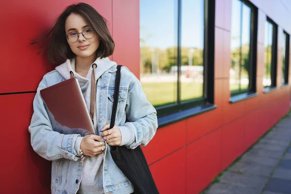 Istruzione, apprendimento e gioventù. Ritratto all'aperto di sognante giovane donna pensierosa in occhiali, tenendo il computer portatile come classi di finitura, testa al co-working spazio di lavoro freelance, fotocamera sorridente — Foto Stock