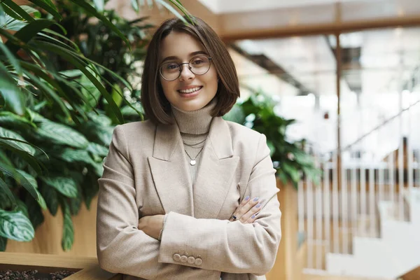 Concepto de carrera, educación y mujeres. Retrato de cerca de la joven empresaria elegante vestíbulo de pie, esperando a asistente personal, hablando con su compañero de trabajo durante la conferencia, la cámara sonriente feliz —  Fotos de Stock