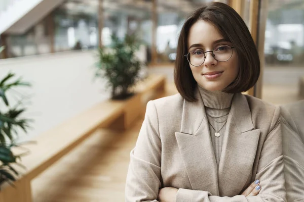 Retrato de una joven profesional y segura de sí misma que trabaja en la venta al por menor, la industria empresarial, promover la empresa, anunciar unirse a su equipo, sonriendo seguro de sí mismo y satisfecho en el stand de la cámara en el pasillo — Foto de Stock