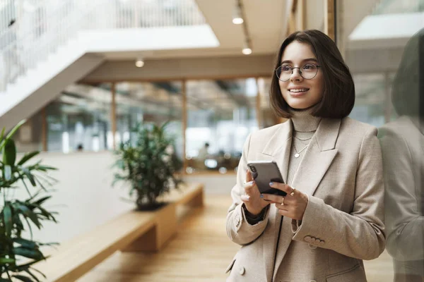 Portret van succesvolle vrolijke glimlachende vrouw net klaar met een ontmoeting met zakenpartners, ondertekende deal bedrijf, het houden van mobiele telefoon en kijk weg met dromerige tevreden uitdrukking — Stockfoto