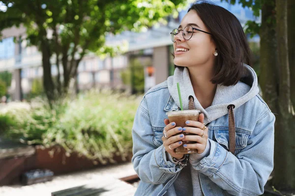 Yaşam tarzı, kadınlar ve duygular. Şehir parkında gözlüklü mutlu bir kızın açık hava portresi. Neşeli bakışlar, gülümsemeler. Baharın tadını çıkarmak, favori kafeden kahve içmek. — Stok fotoğraf