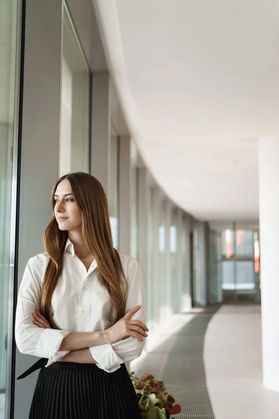 Business and women concept. Elegant successful female entrepreneur looking out window as standing office corridor, contemplating view satisfied with good business deal, meeting went well — Stock Photo, Image
